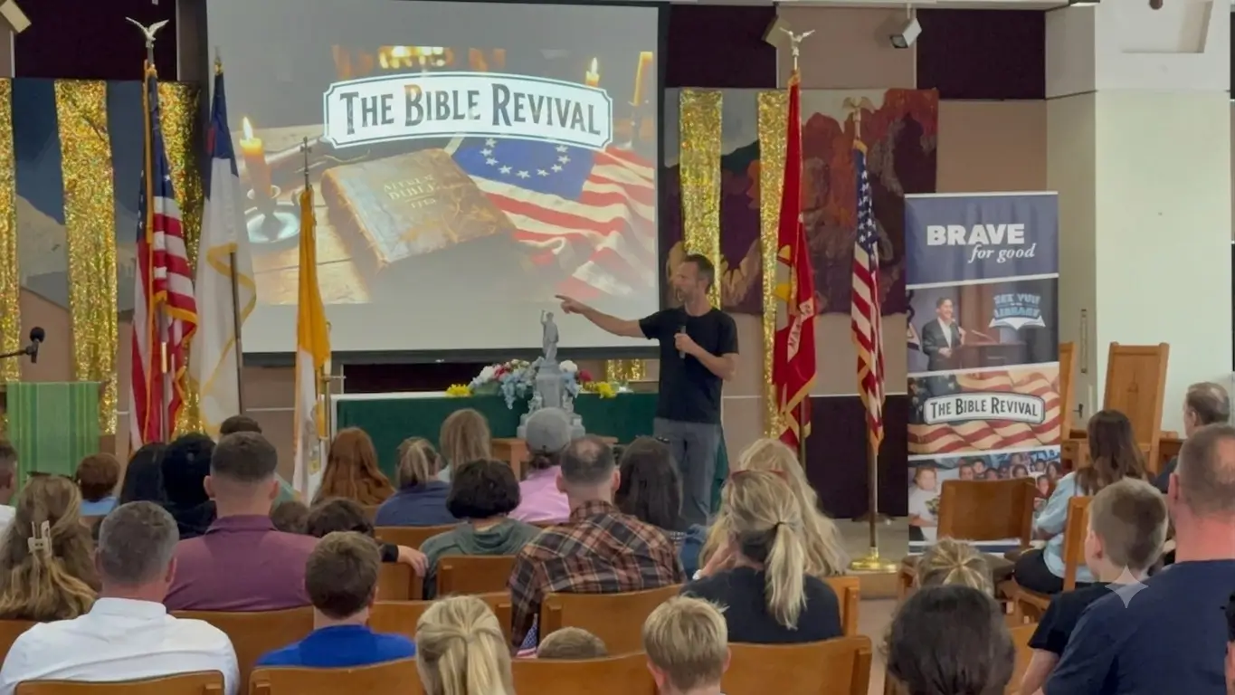 Kirk Cameron speaking to a seated audience at a Bible Revival assembly