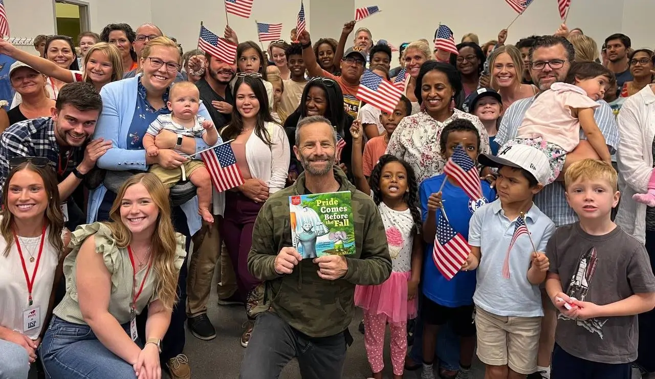 Kirk Cameron and a room full of families holding American flags at a Brave Story Hour